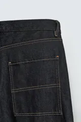 Pantalón de jean negro de corte amplio, con bolsillos delanteros y traseros, presilla portaherramientas en la pierna derecha y costuras a contratono.