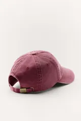 Gorra color borgoña con bordado dorado de la marca Zara, con la inscripción "Zara" y "A Coruña 1975".