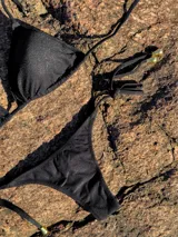 Conjunto de bikini con estampado animal print blanco y negro. El corpiño es de triángulos movibles con tiras finas para atar al cuello y a la espalda, con almohadillas desmontables. La bombacha es colaless con tiras finas para atar a los costados.