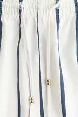Short de tiro alto con cintura elástica fruncida, cordón de ajuste con cuentas metálicas y bolsillos laterales. Diseño a rayas verticales en color azul marino y blanco.