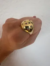Anillo dorado con forma irregular y piedras de colores incrustadas.