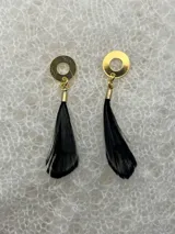 Par de aros colgantes con base redonda negra, detalles dorados y plumas negras.