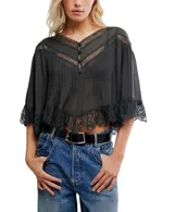 Blusa ligera de color gris oscuro con silueta corta y aireada. Presenta detalles de encaje en el escote en V, en los hombros y en el ruedo. Tiene un frente con botones y mangas 3/4 amplias.