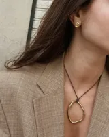 Collar con dije circular irregular de alpaca y plata 925, con hilo de algodón natural.