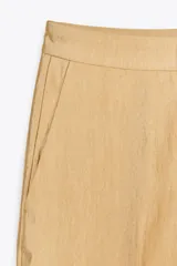 Pantalón de vestir color arena, de tiro medio y corte recto, confeccionado en hilatura con viscosa. Cuenta con bolsillos laterales, raya planchada en delantero y cierre frontal con cremallera, botón y gancho metálico.