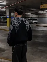 Sweater negro con cuello redondo y diseño geométrico en gris en la parte superior del pecho y hombros.