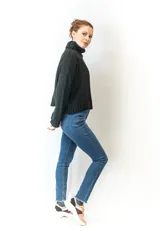 Sweater tejido color crudo, con cuello alto y diseño de trenzas verticales en el frente.