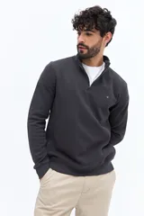 Buzo de algodón color verde musgo, con cuello alto y cierre frontal parcial. Presenta puños y cintura acanalados, y un pequeño logo bordado en el pecho.