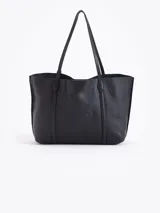 Cartera shopper negra de cuero vacuno flor, con grabados de cerezas distribuidos en la superficie. Tiene acceso mediante imán, manijas de cuero y un tag con mini aplique de cereza. Incluye un bolsillo desmontable con cierre metálico en su interior.