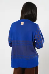 Buzo de punto color azul con diseño de círculos en tonos más oscuros, de corte holgado y mangas largas.