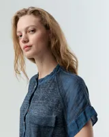 Remera celeste de lino y ramio, con corte boxy, manga japonesa, cuello mao, media cartera con broches metálicos y bolsillo plaqué con efecto de tapa.