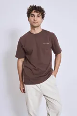 Remera de manga corta color marrón oscuro con cuello redondo y un pequeño texto bordado en blanco en el pecho.