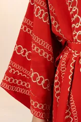Kimono corto rojo con estampado de cadenas doradas, mangas amplias y cinturón a juego.