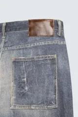 Pantalón de jean azul con lavado gastado, corte holgado y cinco bolsillos.