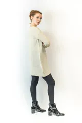 Vestido corto tejido color beige, con mangas largas y corte holgado, inspirado en el diseño de un buzo clásico.