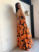 Vestido largo con estampado floral en tonos naranja y negro, espalda descubierta y abertura lateral en la pierna.