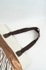 Bolso tipo tote con estampado de estrellas negras sobre fondo beige y una franja horizontal negra con glitter.