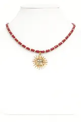 Collar corto de cuentas tubulares color rojo coral, separadas por pequeñas cuentas doradas. Dije de sol dorado con centro de circonias.