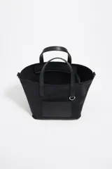 Bolso tote negro de nylon con doble asa corta y correa bandolera ajustable. Incluye logo de la marca en etiqueta frontal.
