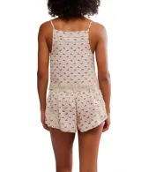 Conjunto de pijama color crema con estampado de flores rojas, compuesto por un top de tirantes con escote redondo y shorts a juego. Ambos tienen detalles de encaje en los bordes.
