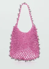 Bolso shopper tejido de color rosa con abalorios plateados en el borde y en las asas.