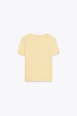 Camiseta corta de algodón color amarillo pastel, de corte recto, cuello redondo y manga corta. Detalle de costura marcada en la espalda.