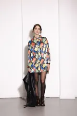 Camisa estampada con hojas de colores sobre fondo negro, de corte amplio y ruedo curvo.