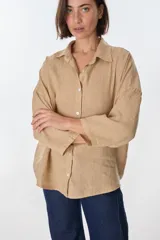 Camisa de lino color beige, de manga larga y corte holgado, con cuello clásico y cierre frontal de botones.