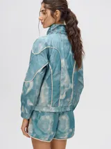 Campera rompevientos estilo biker con capucha desmontable, color celeste con estampado de nubes blancas y detalles en blanco.