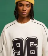 Remera de corte boxy color crema con estampa del número 96 en el frente y detalles en negro en cuello y mangas.