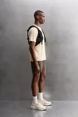 Camiseta deportiva marrón confeccionada en tejido técnico ligero y elástico con estructura perforada. Cuello redondo, manga corta y bajo asimétrico con aberturas laterales. Detalle de logo estampado.