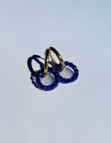 Par de aros colgantes con argollas doradas y dijes circulares de resina transparente con incrustaciones de strass de colores. El dije mide aproximadamente 1.5cm de diámetro.