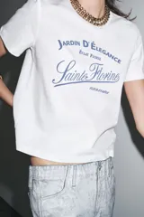 Camiseta blanca de cuello redondo y manga corta con estampado de texto en azul.