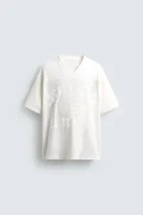 Camiseta blanca de corte holgado con cuello en V y mangas cortas. Presenta un diseño de malla con diferentes texturas combinadas a tono y estampado frontal con la inscripción "Legacy Crew 95 Elite Mode".