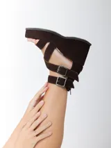 Sandalias de cuero marrón con acabado en gamuza, taco de 8 cm y plataforma forrada. Diseño con doble tira ajustable con hebillas metálicas y cierre trasero.