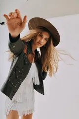 Chaqueta de cuero negra con detalles en cuero marrón en cuello y solapas, con apliques metálicos.