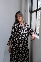 Vestido largo de corte amplio con estampado animal print en tonos negro y beige, cuello camisero y mangas largas.