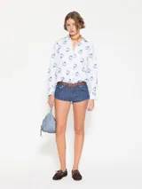 Camisa blanca de poplin con lycra y estampado de hongos en azul. Tiene ojales color bordó en la cartera y puños, y costura de refuerzo en forma de X en el puño.