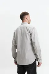 Camisa de manga larga gris oscuro, corte slim, con cartera abotonada, dos bolsillos frontales con botón y confeccionada en 100% algodón.