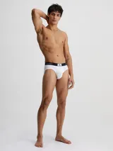 Pack de tres slips Calvin Klein en colores negro, blanco y gris, con cintura elástica negra con logo de la marca.