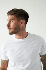 Remera básica color marrón claro, de corte regular, manga corta, cuello redondo y logo bordado en el pecho.