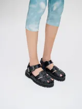 Sandalias romanas color verde oliva, con tiras entrecruzadas y hebilla lateral. Suela de goma negra con plataforma de 3cm. Fabricadas en cuero vacuno.