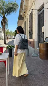 Mochila bandolera color marrón con herrajes color peltre. Tiene un compartimento principal amplio con cierre, un bolsillo frontal con cierre y dos bolsillos laterales abiertos. Incluye correa ajustable para usar al hombro o cruzada.