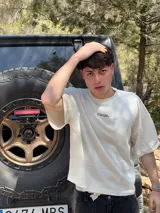 Remera marrón con estampado de un reloj dorado y la frase "Who wears a watch in Ibiza?".