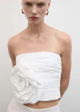 Top blanco strapless con diseño fruncido y maxi flor en el lateral.