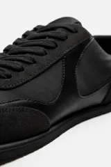 Zapatilla deportiva monocolor negra de cordones, con suela ultrafina y logo lateral.