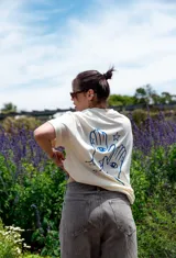 Remerón color crema con estampado en la espalda de dos manos con ojos en las palmas y estrellas azules.