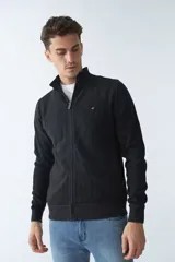 Campera marrón de algodón con cierre frontal, cuello alto, bolsillos laterales, puños y logo bordado en el pecho.