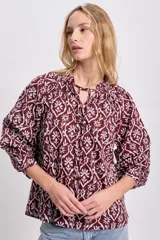 Blusa de manga larga color bordó con estampado floral en blanco, cuello redondo con lazo ajustable y corte holgado.