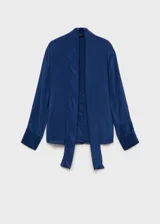 Blusa azul con lazo al cuello, de tejido fluido y satinado, con cierre oculto de botones y mangas largas abotonadas.